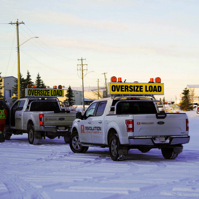 Two Revolution Crane & Transport escort trucks parked on site